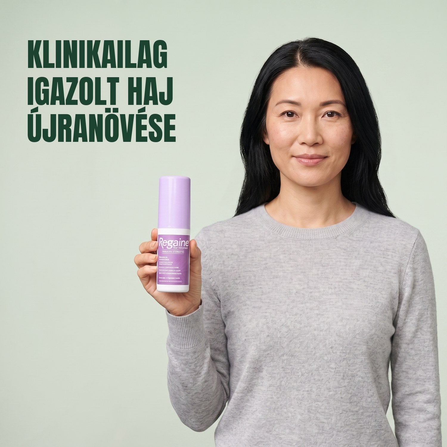 Nő tartja a Regaine for Women Minoxidil 2% oldat csomagját, zöld háttér előtt