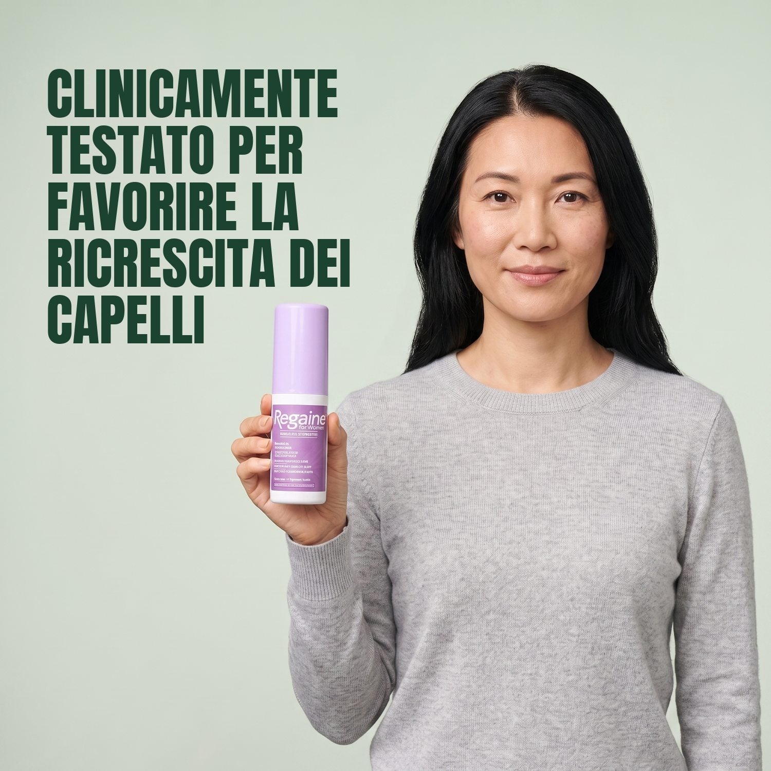 Woman holding the Regaine for Women Minoxidil 2% lotion pack against a green background
