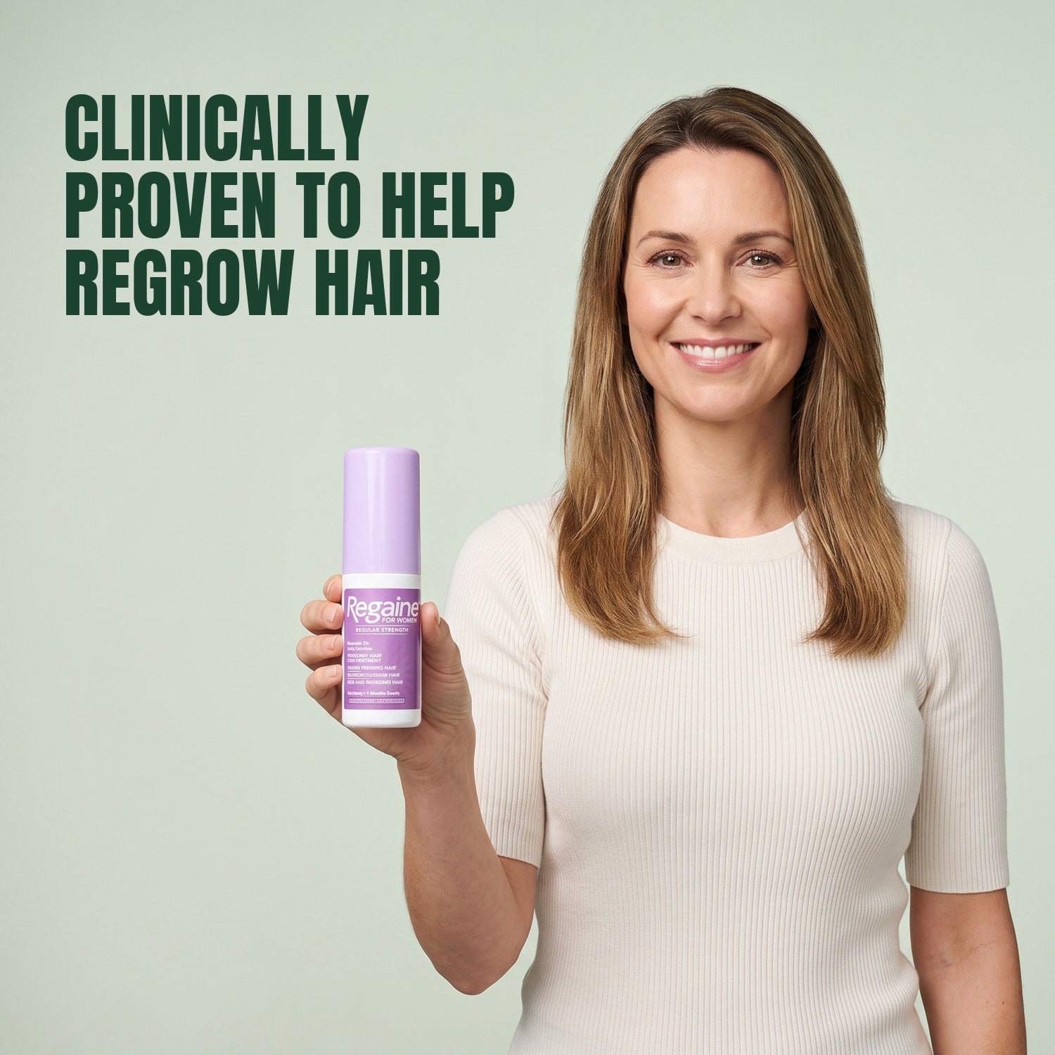 Woman holding a Regaine for Women Minoxidil 2% lotion bottle against a green background