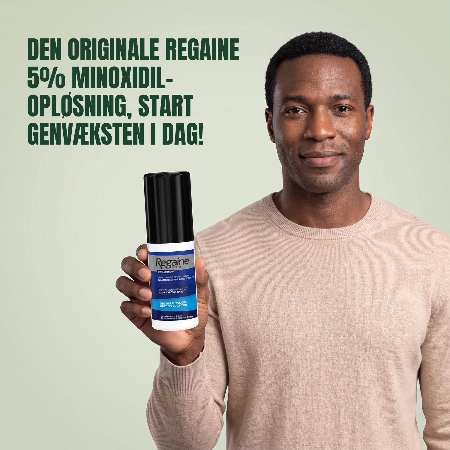 Man holding the Regaine for Men Minoxidil 5% lotion pack against a green background
