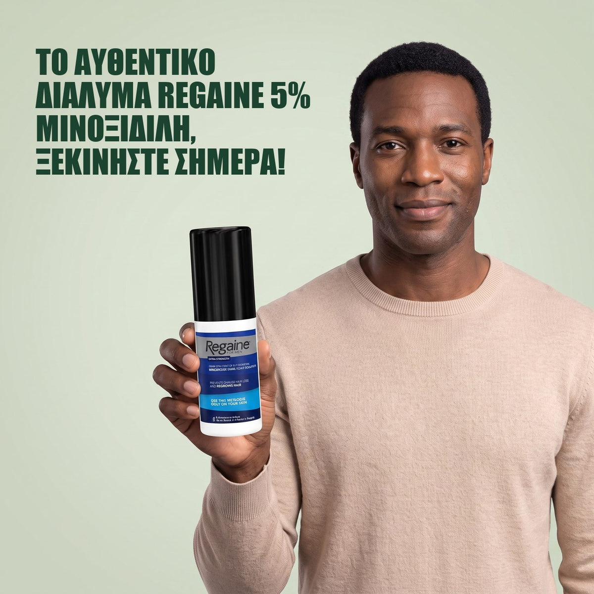 Άντρας κρατά τη συσκευασία Regaine for Men Minoxidil 5% διάλυμα σε πράσινο φόντο