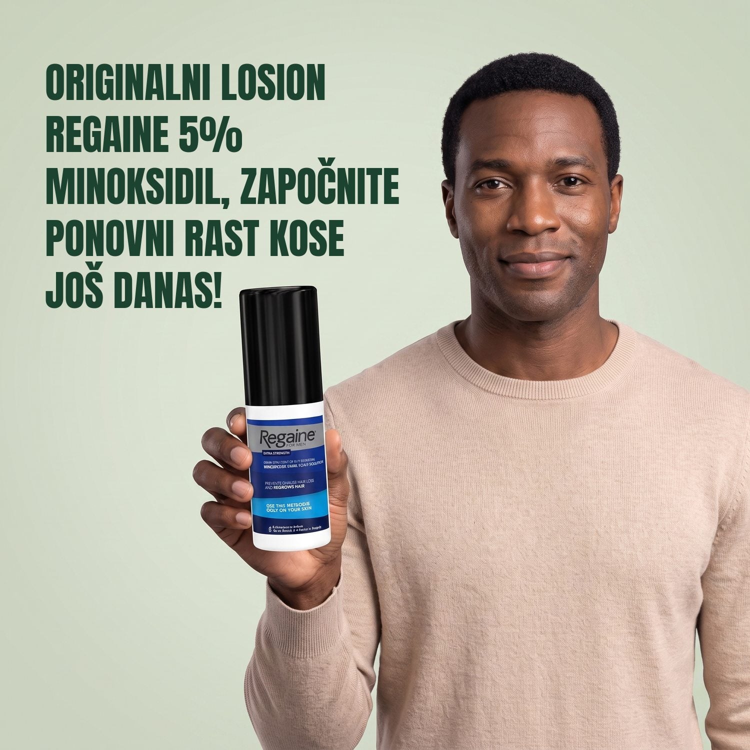 Muškarac drži pakiranje Regaine for Men Minoxidil 5% losiona na zelenoj pozadini