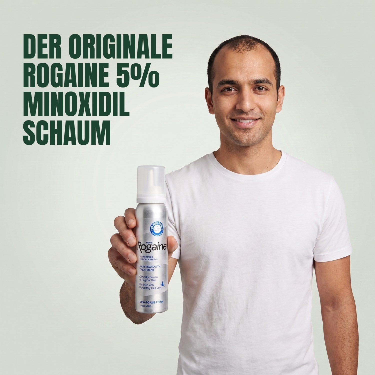 Man holding the Rogaine 5% minoxidil foam carton with a foam can against a green background