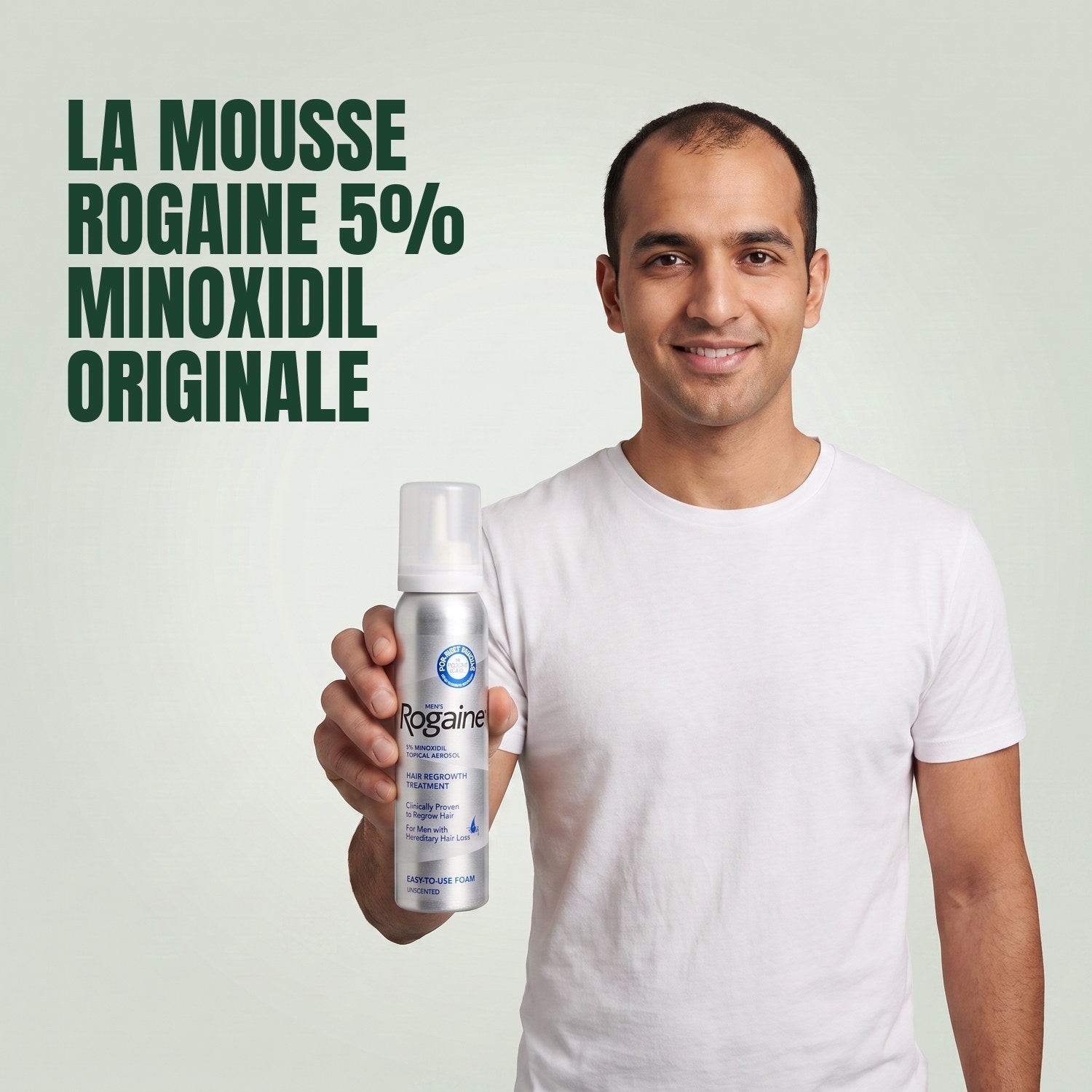 Man holding the Rogaine 5% minoxidil foam carton with a foam can against a green background