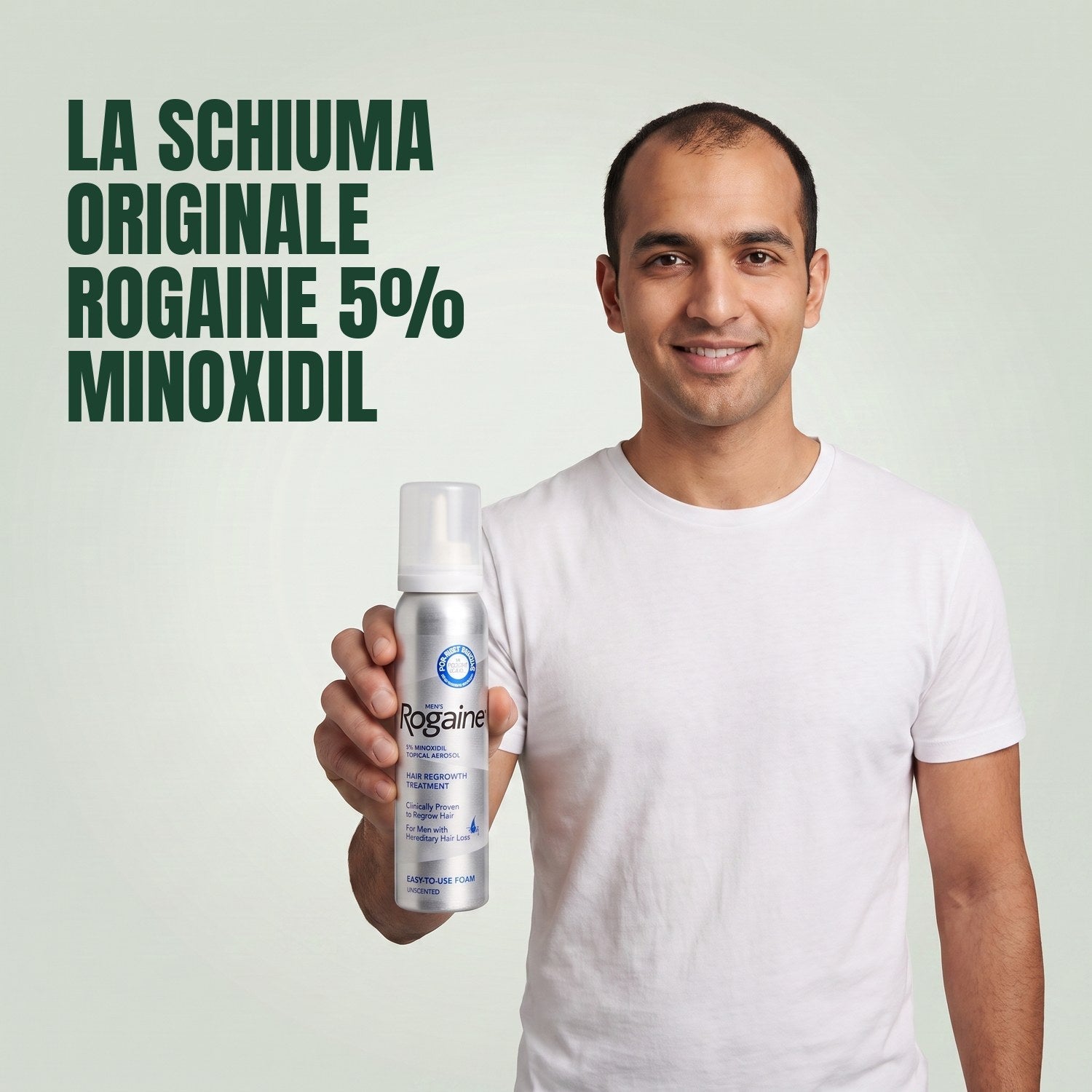 Man holding the Rogaine 5% minoxidil foam carton with a foam can against a green background