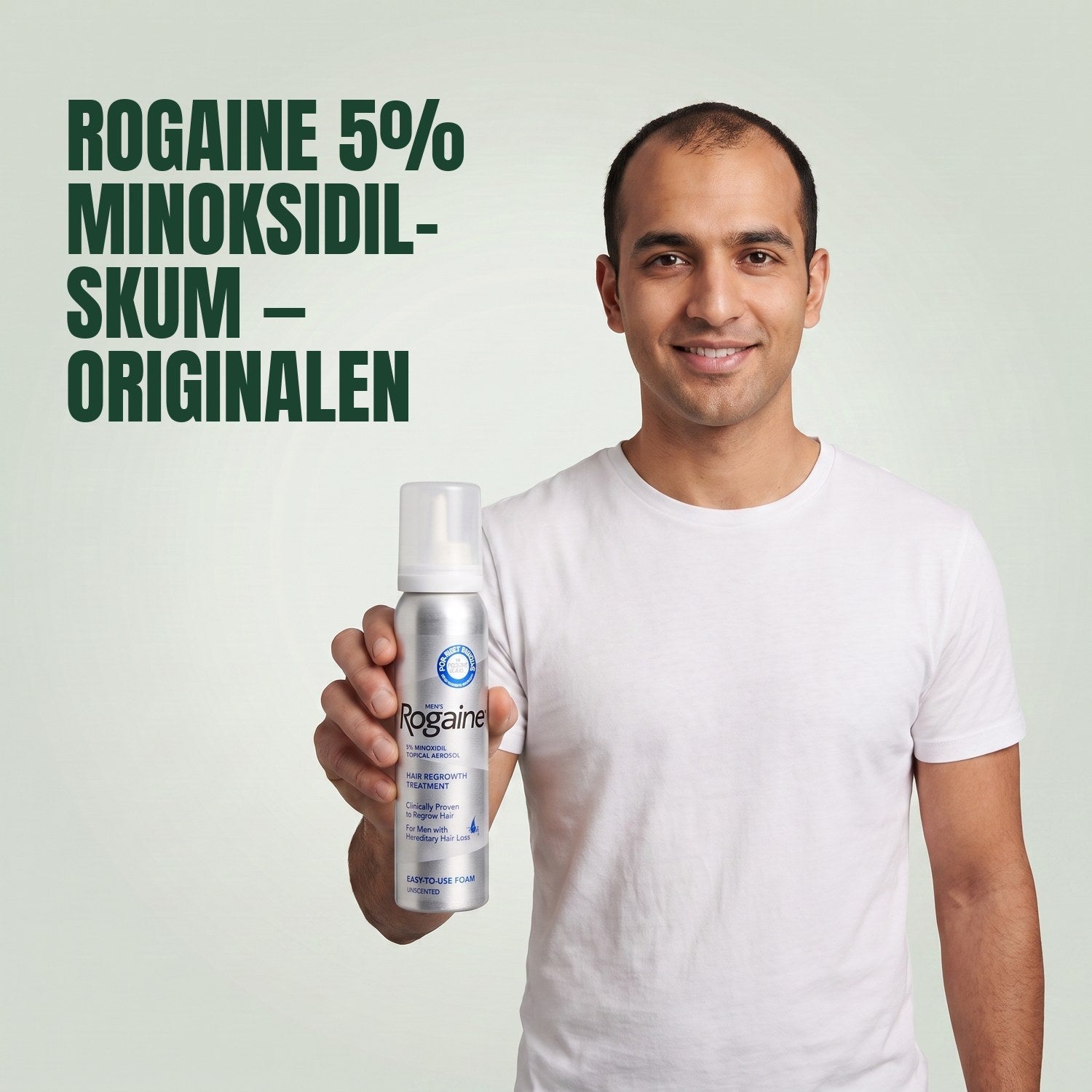 Man holding the Rogaine 5% minoxidil foam carton with a foam can against a green background