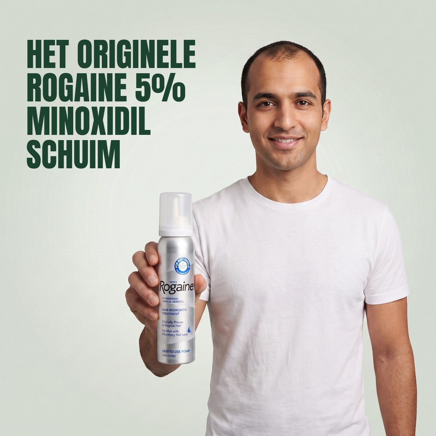 Man holding the Rogaine 5% minoxidil foam carton with a foam can against a green background