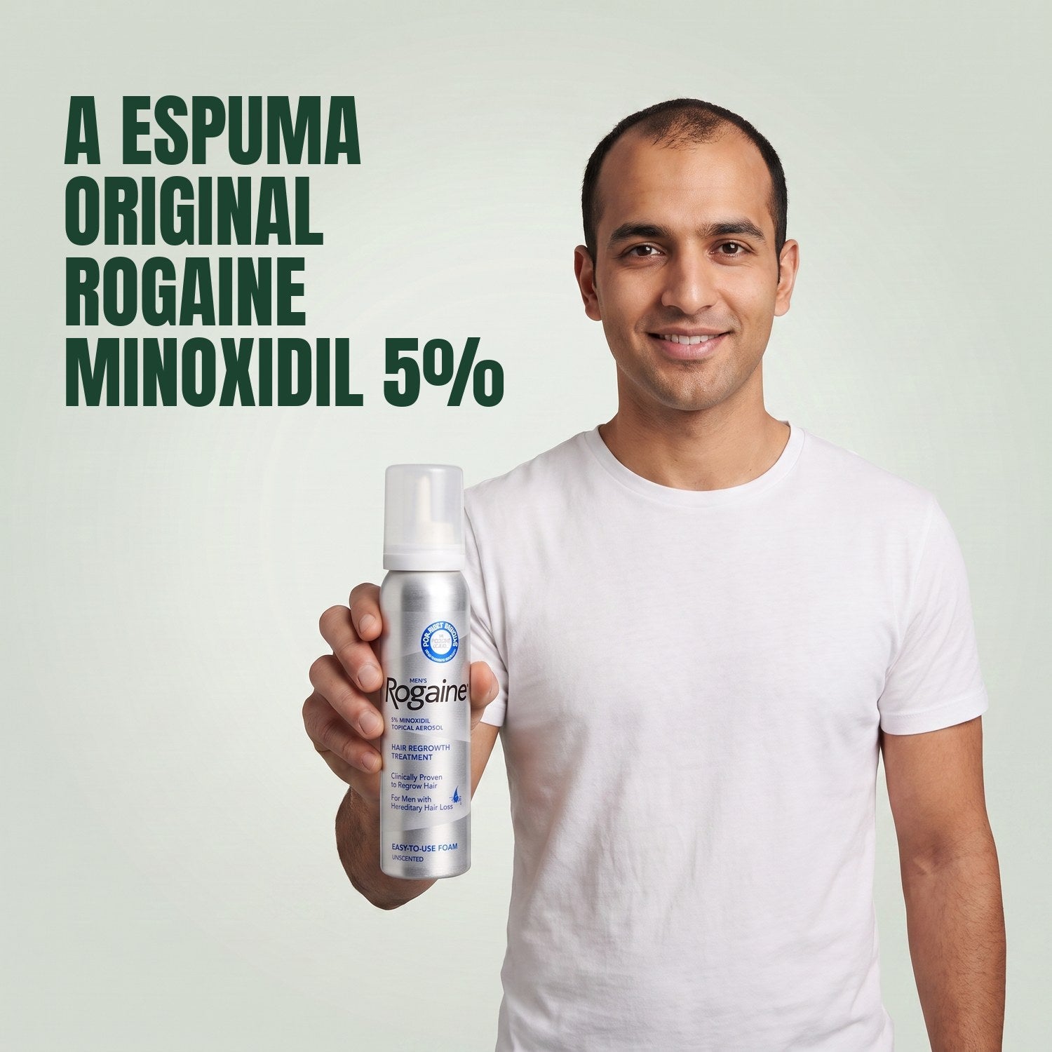Homem segurando a caixa de espuma Rogaine 5% minoxidil com uma lata de espuma em fundo verde
