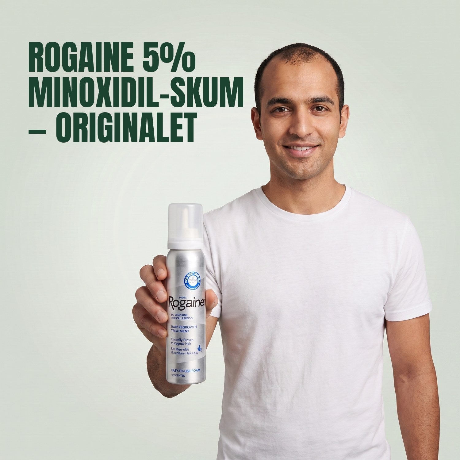Man holding the Rogaine 5% minoxidil foam carton with a foam can against a green background
