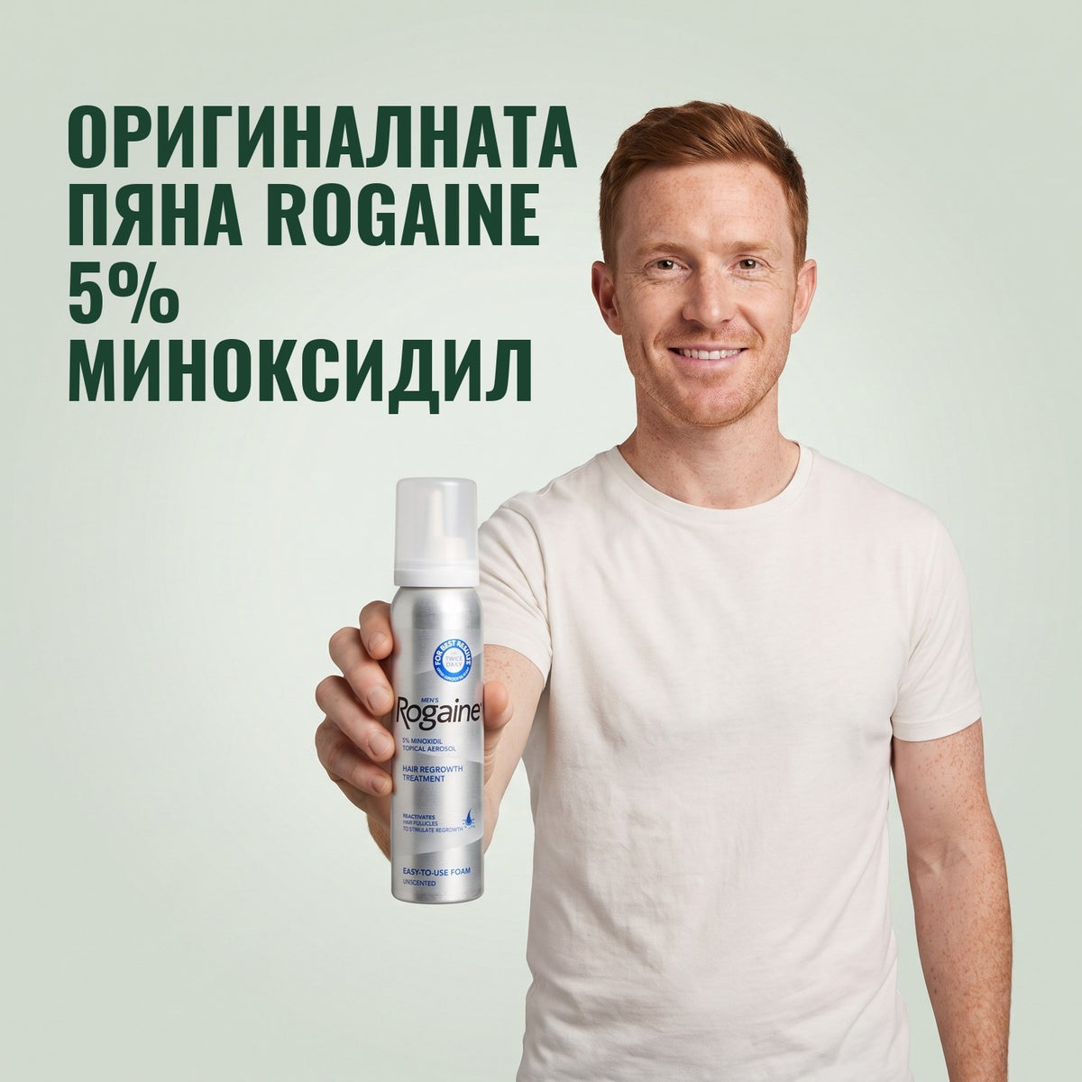 Мъж държи кутия пяна с 5% миноксидил Rogaine на зелен фон