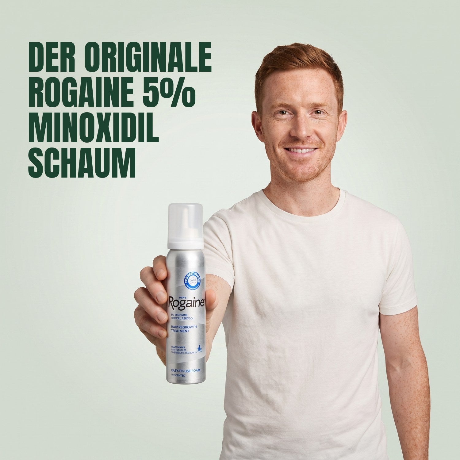 Man holding a Rogaine 5% minoxidil foam can against a green background