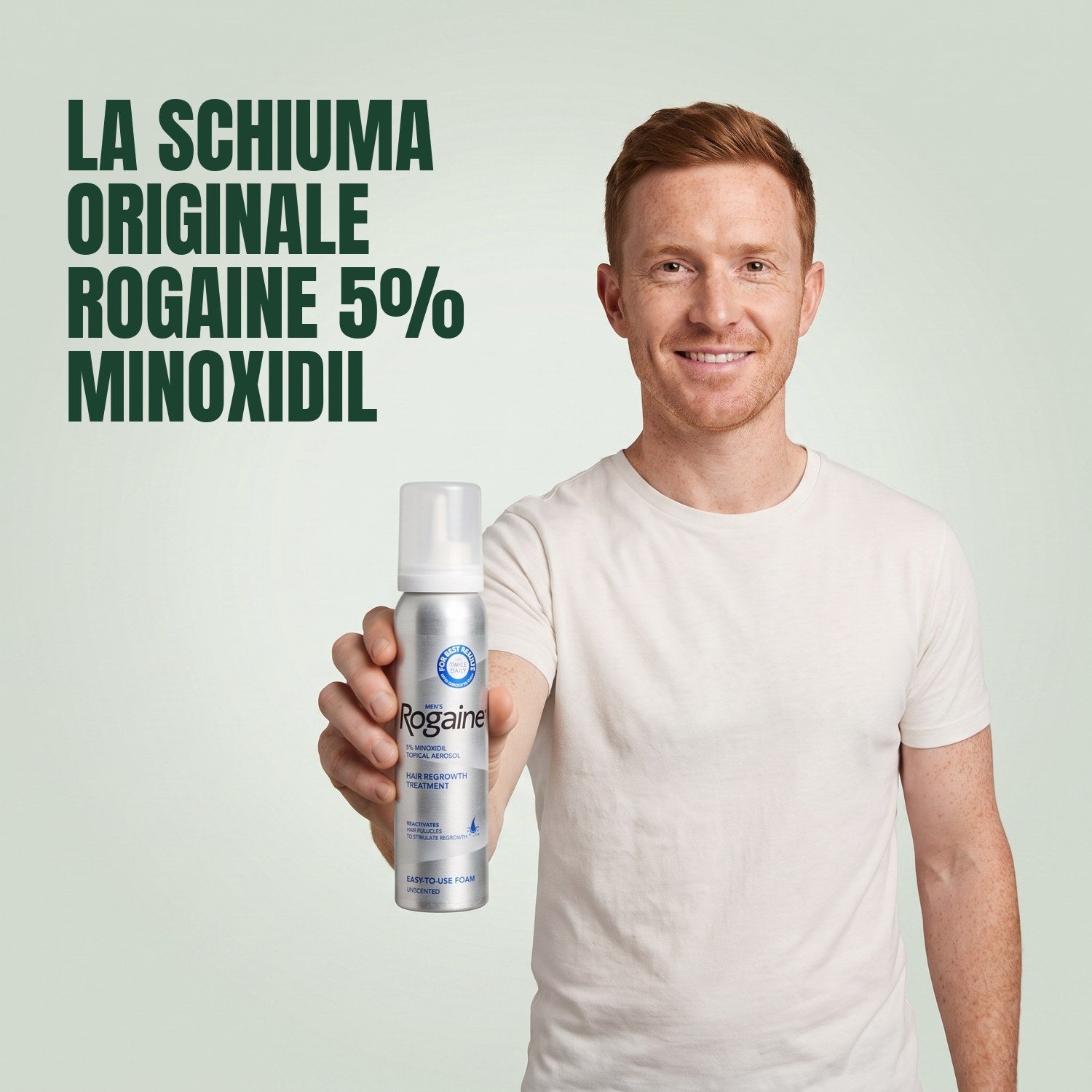 Man holding a Rogaine 5% minoxidil foam can against a green background