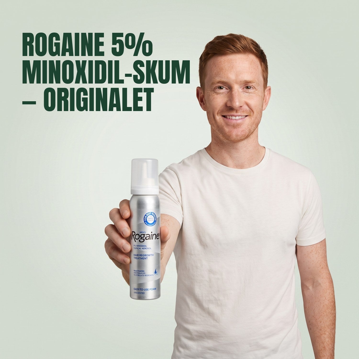 Man håller en burk Rogaine 5% minoxidilskum mot en grön bakgrund