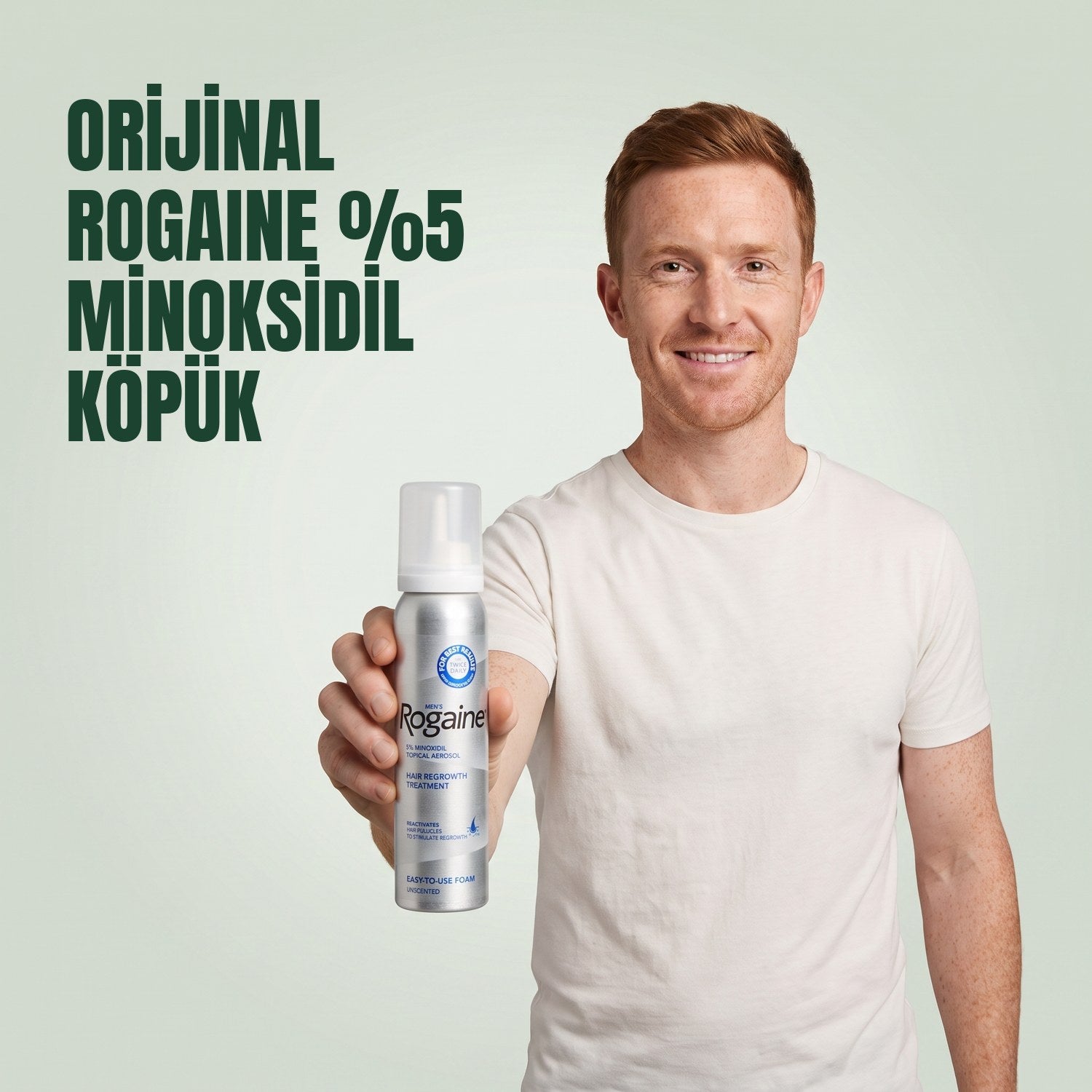 Yeşil arka planda elinde Rogaine %5 minoksidil köpük kutusu tutan erkek