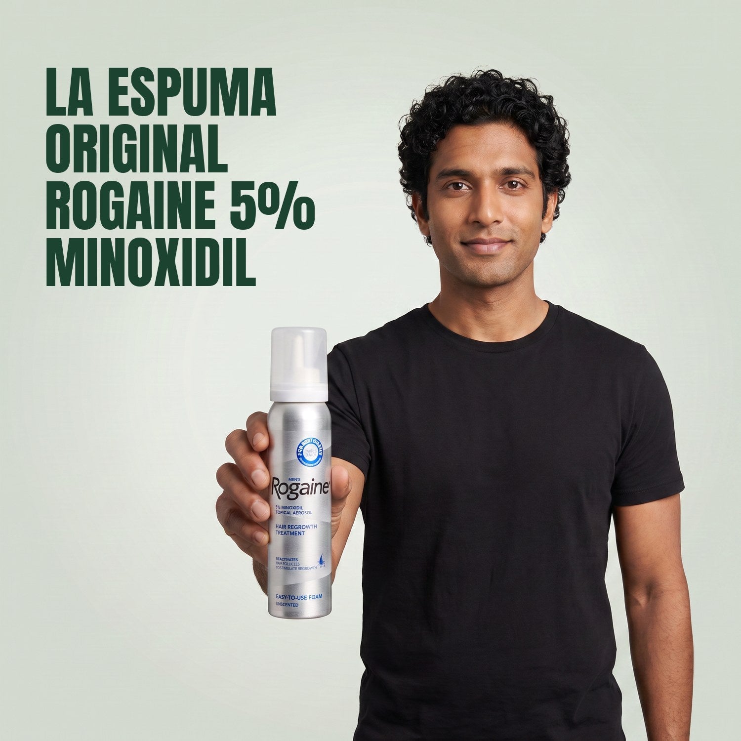 Man holding the Rogaine 5% minoxidil foam carton with a foam can against a green background
