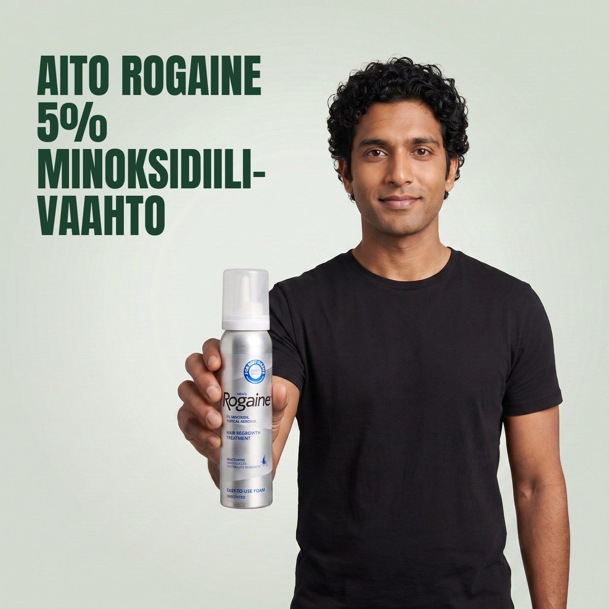 Man holding the Rogaine 5% minoxidil foam carton with a foam can against a green background