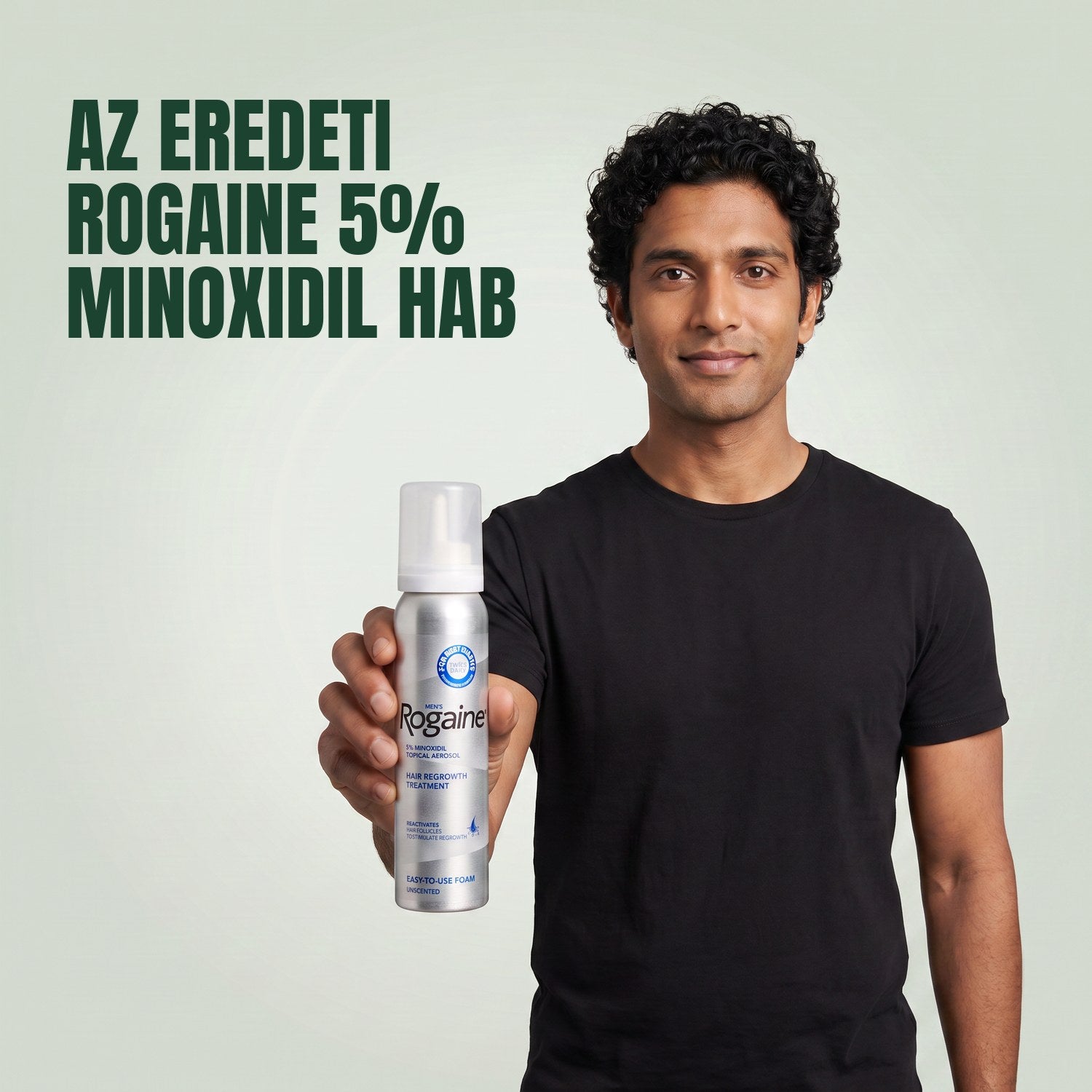 Férfi tartja a Rogaine 5% minoxidil hab csomagolását egy hab dobozzal, zöld háttér előtt