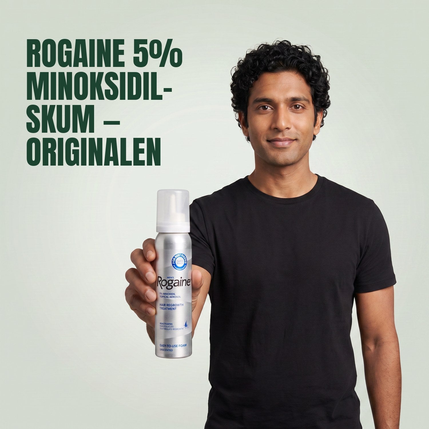 Man holding the Rogaine 5% minoxidil foam carton with a foam can against a green background