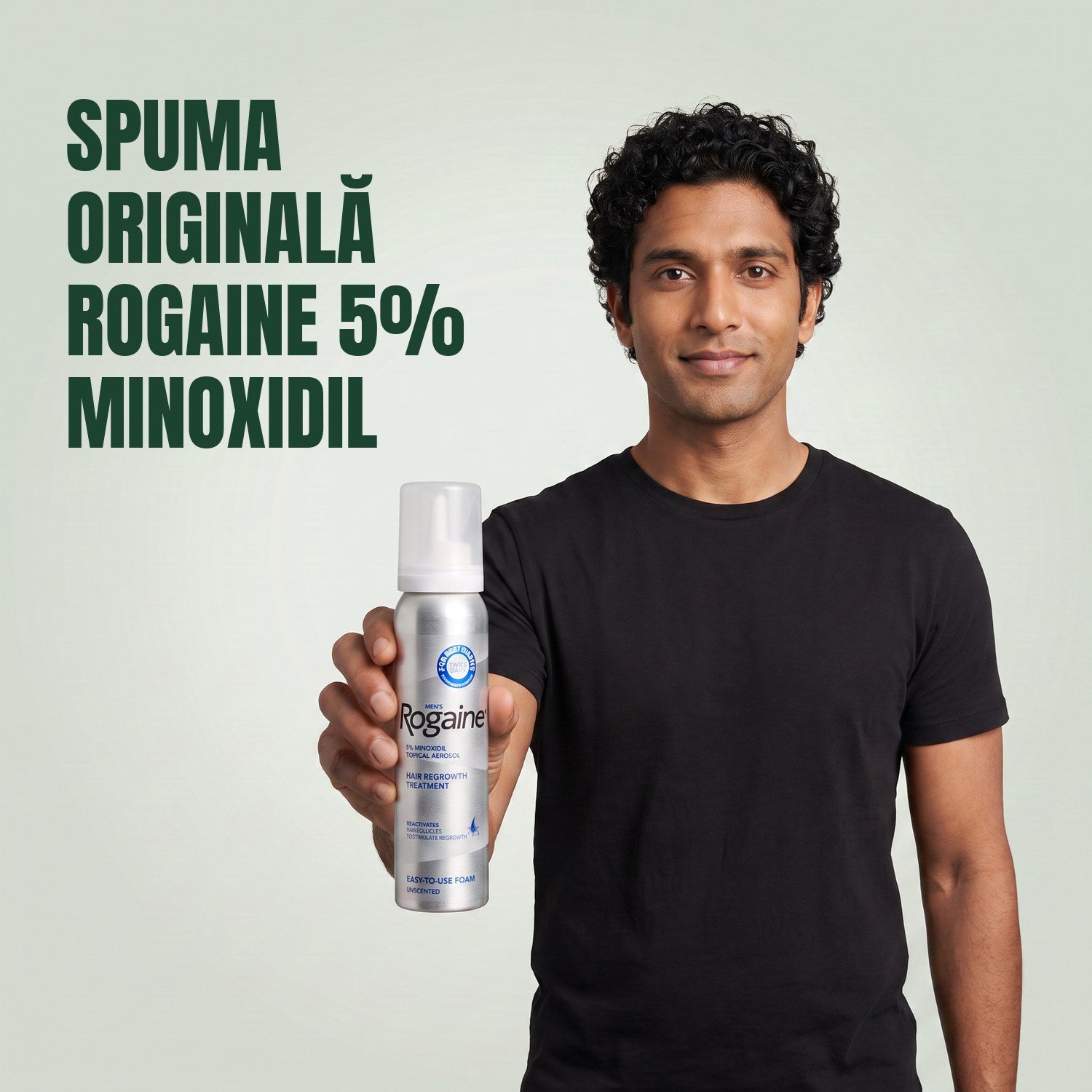 Bărbat ținând în mână cutia Rogaine 5% minoxidil spumă, cu o cutie de spumă alături, pe fundal verde