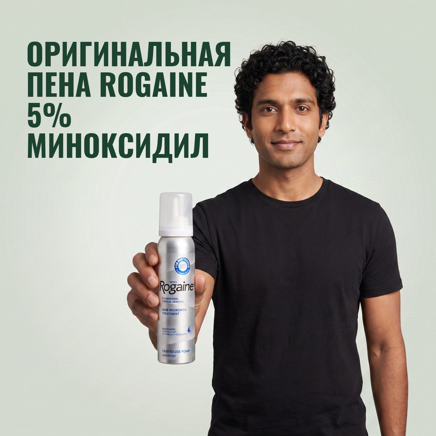 Man holding the Rogaine 5% minoxidil foam carton with a foam can against a green background