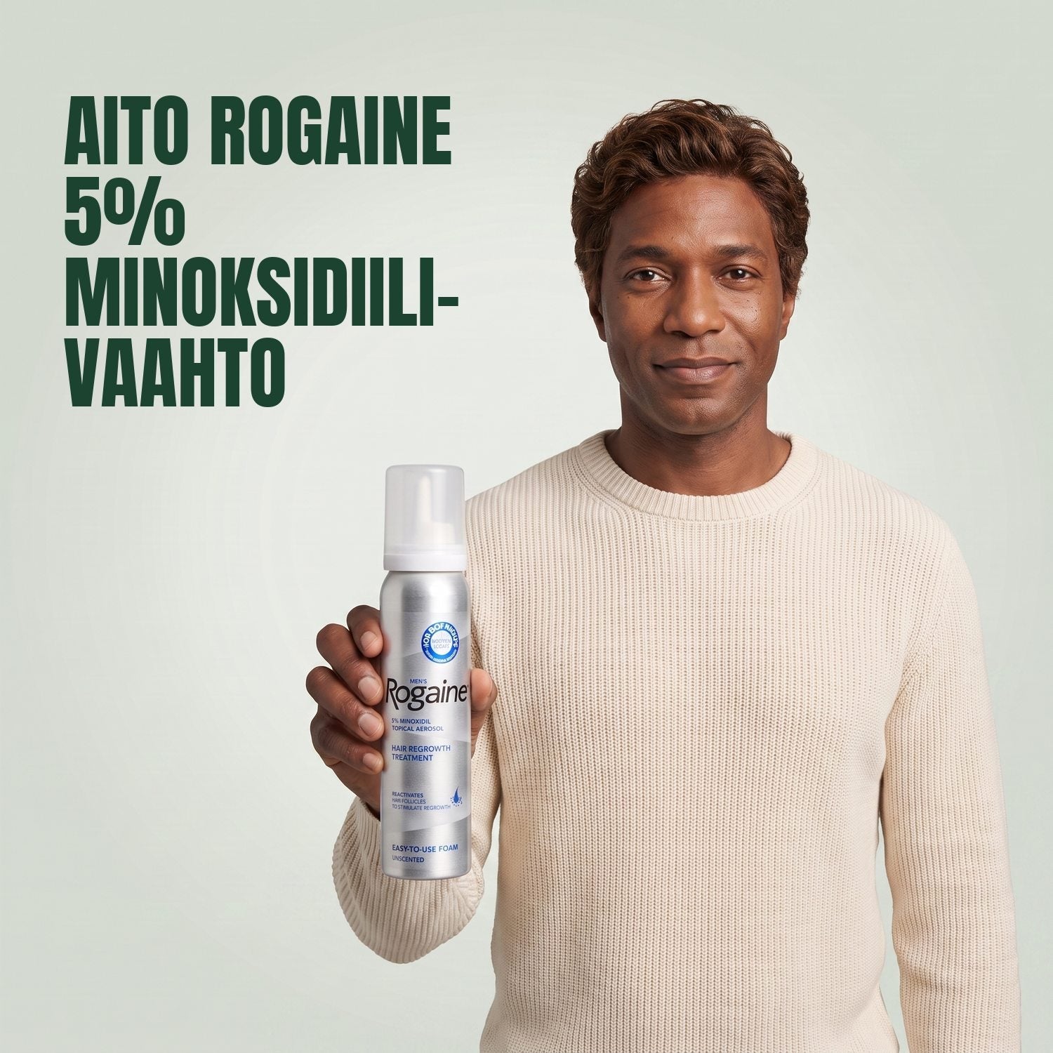 Man holding the Rogaine 5% minoxidil foam carton with a foam can against a green background