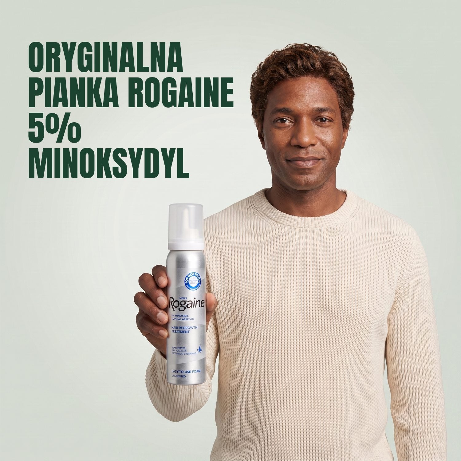 Mężczyzna trzyma pudełko pianki Rogaine 5% minoksydyl z puszką pianki na zielonym tle