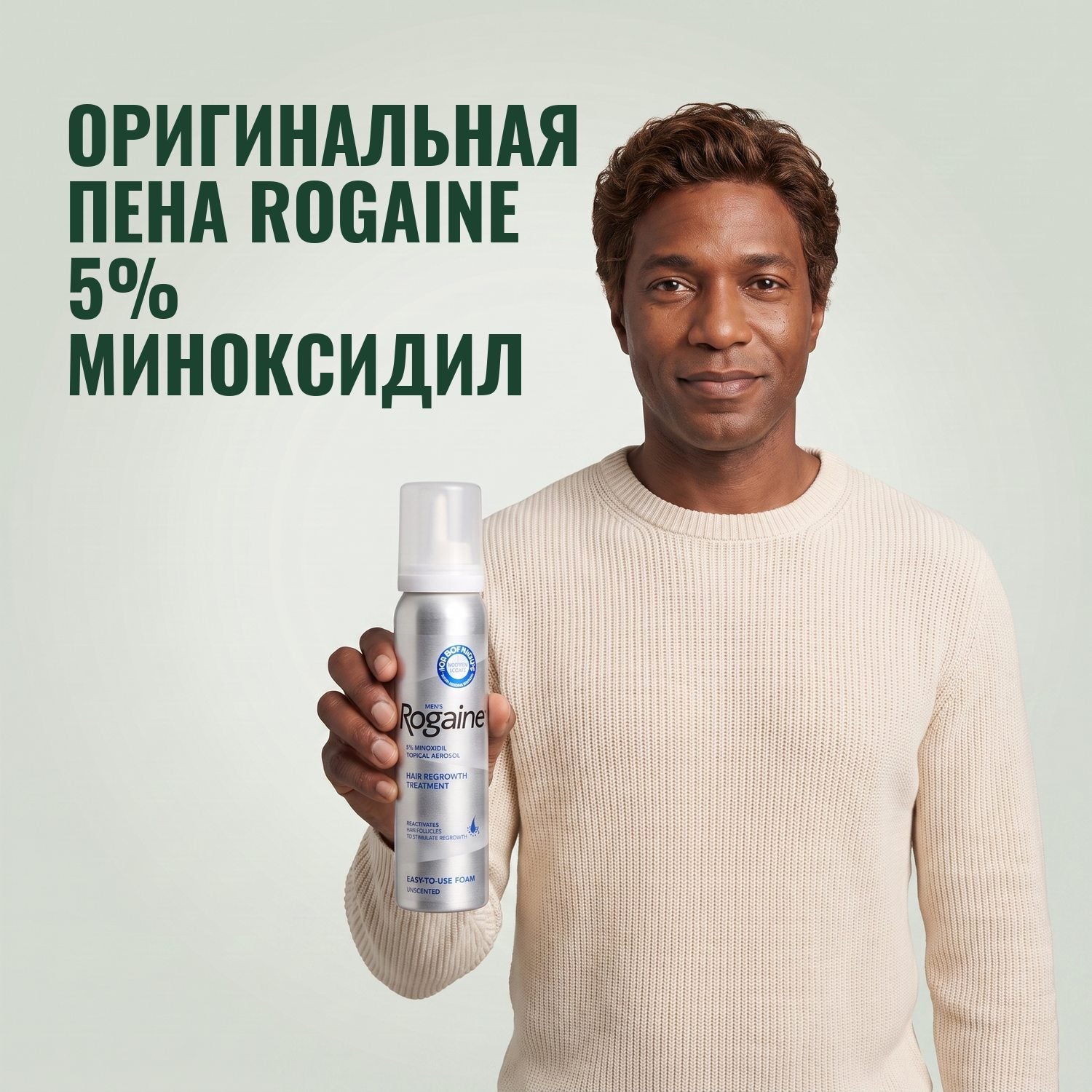Man holding the Rogaine 5% minoxidil foam carton with a foam can against a green background