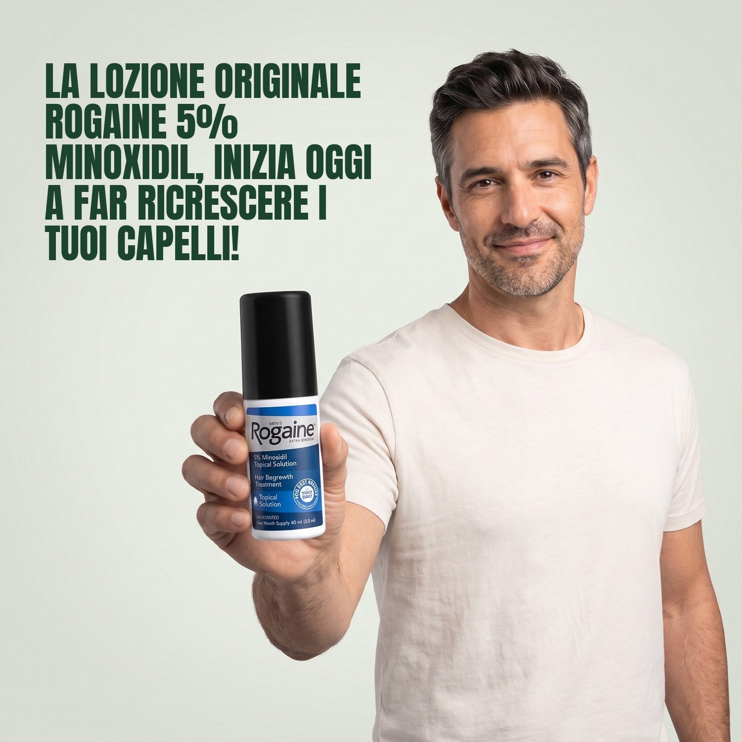 Man holding a Rogaine 5% minoxidil topical solution bottle against a green background