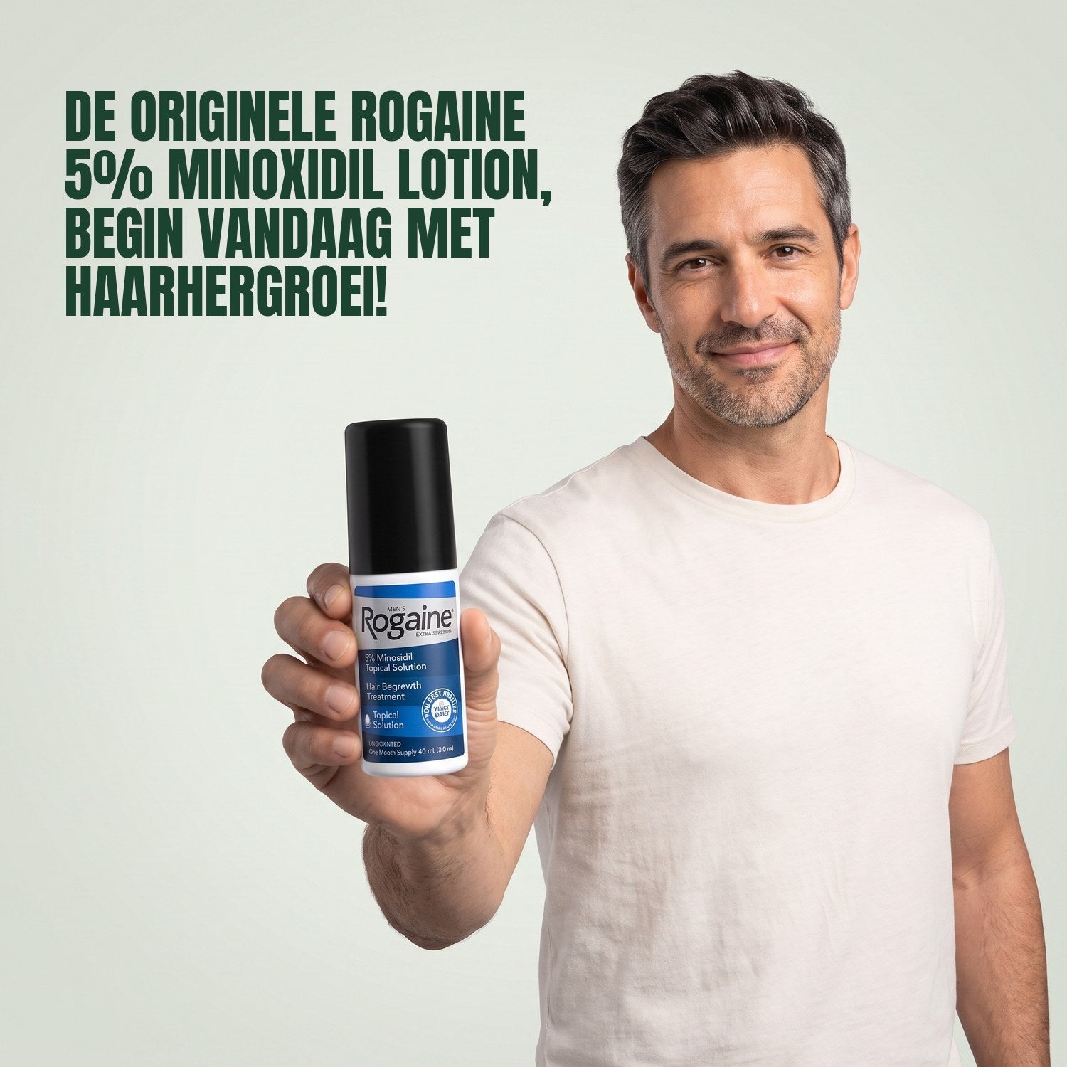 Man holding a Rogaine 5% minoxidil topical solution bottle against a green background