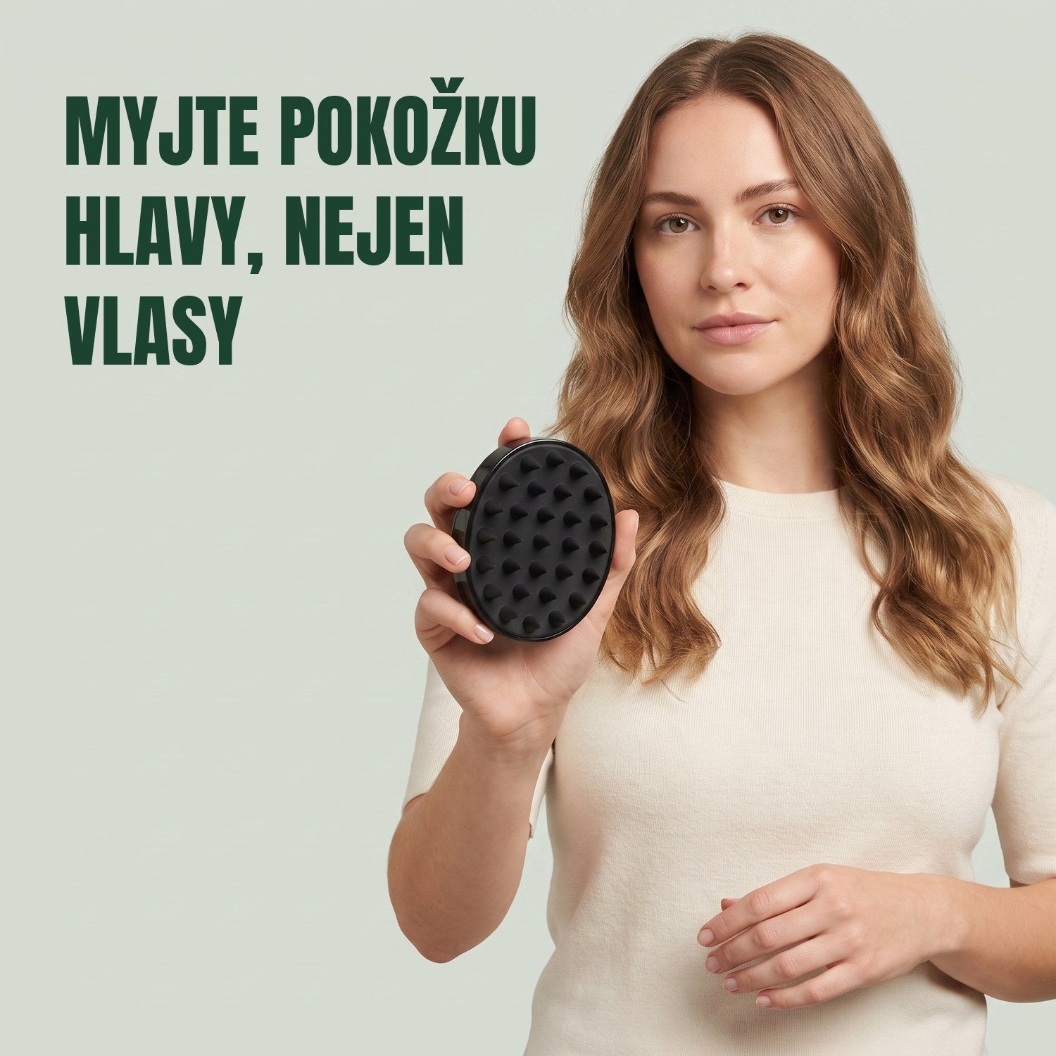 Žena drží masážní kartáč na pokožku hlavy na zeleném pozadí